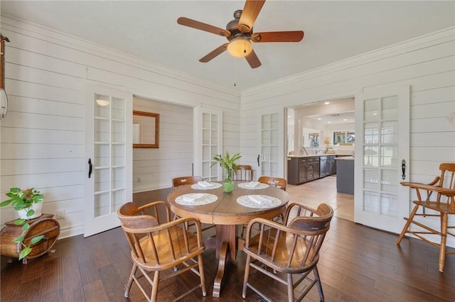 dining room with ceiling fan, wood finished floors, and wood walls