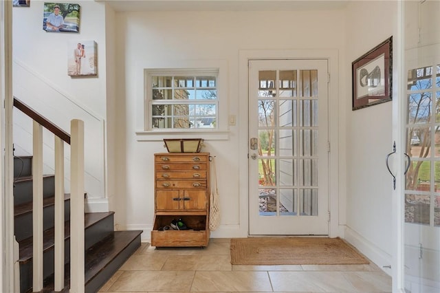 entrance foyer with light tile patterned floors, baseboards, plenty of natural light, and stairs