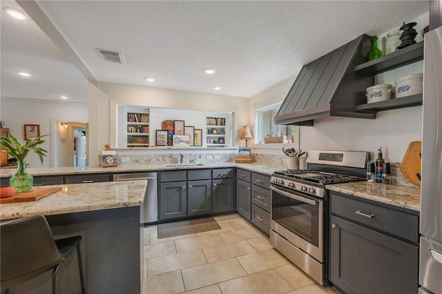 kitchen featuring visible vents, gray cabinetry, light stone counters, appliances with stainless steel finishes, and a sink