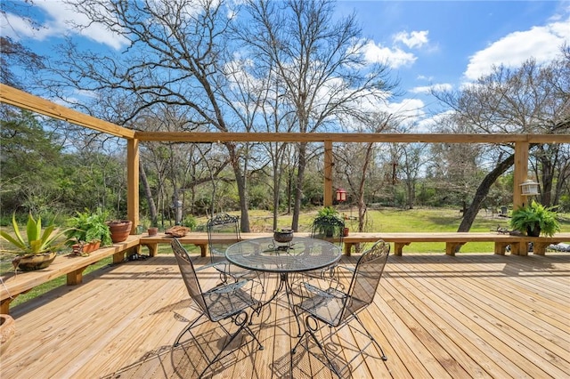 wooden deck with outdoor dining space and a lawn