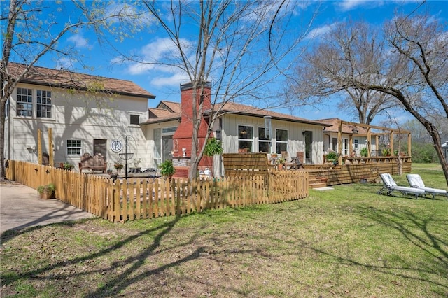 rear view of property featuring a yard, board and batten siding, a fenced front yard, and a chimney