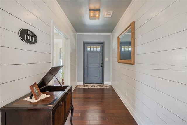 entryway with visible vents, baseboards, dark wood-type flooring, and ornamental molding