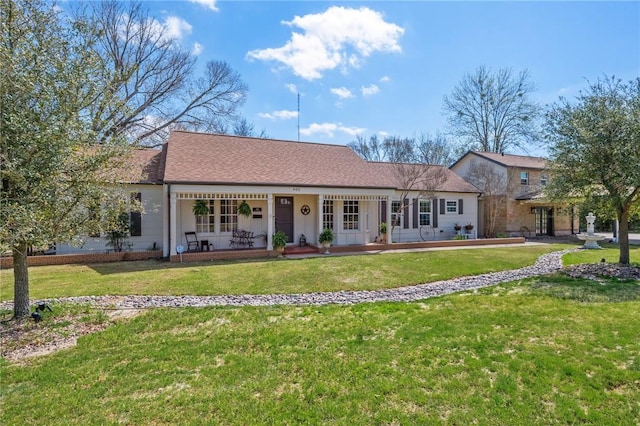 ranch-style home featuring a porch, a front yard, and roof with shingles