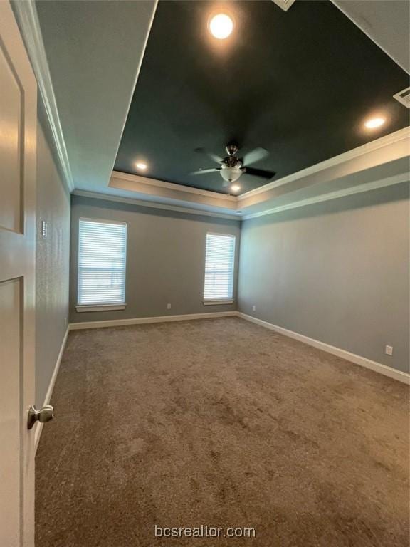 spare room featuring a raised ceiling, crown molding, carpet, and ceiling fan