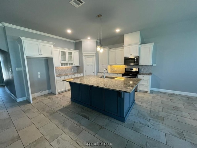 kitchen featuring light stone countertops, backsplash, stainless steel appliances, a center island with sink, and white cabinetry