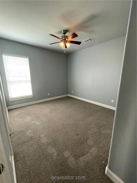 spare room featuring dark carpet and ceiling fan