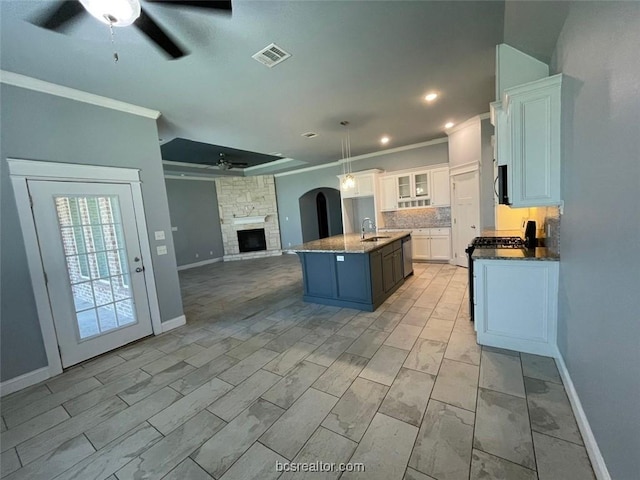 kitchen featuring ornamental molding, stainless steel appliances, sink, white cabinetry, and an island with sink