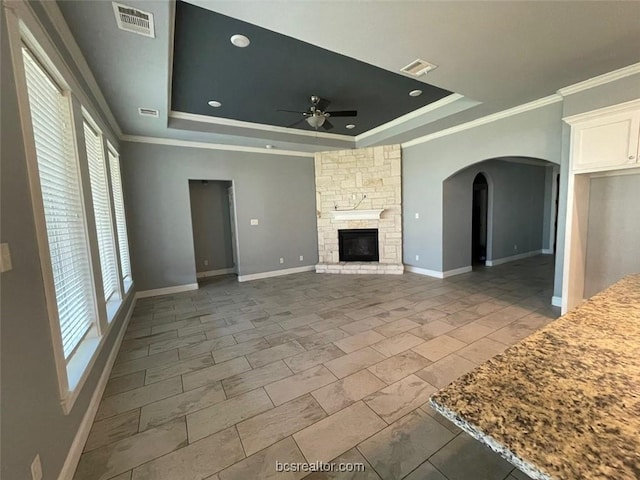 unfurnished living room with a fireplace, a raised ceiling, ceiling fan, and crown molding