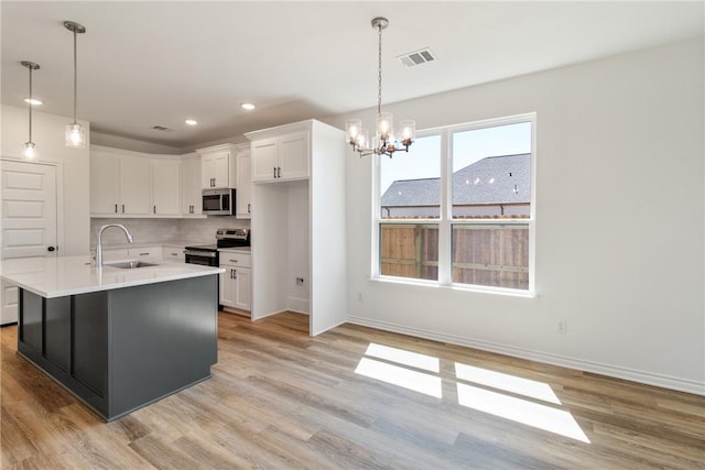 kitchen featuring stainless steel appliances, white cabinetry, light hardwood / wood-style floors, and sink