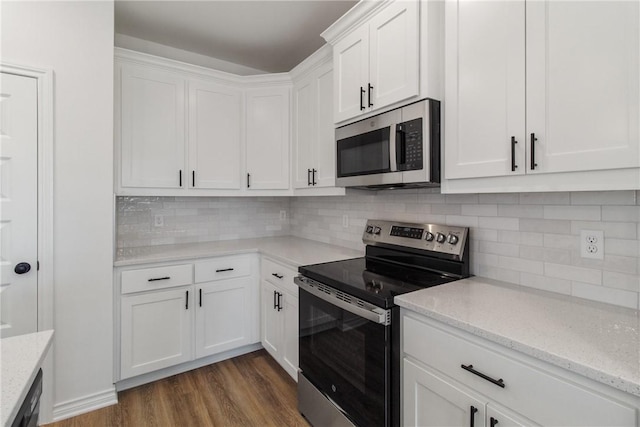 kitchen with appliances with stainless steel finishes, white cabinetry, dark wood-type flooring, and light stone counters