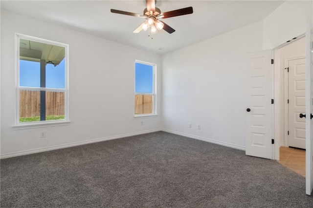 spare room featuring dark carpet and ceiling fan