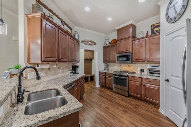 kitchen with light stone countertops, appliances with stainless steel finishes, dark hardwood / wood-style flooring, sink, and decorative light fixtures