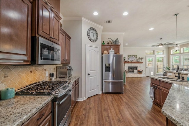 kitchen featuring light stone countertops, sink, stainless steel appliances, dark hardwood / wood-style flooring, and decorative light fixtures