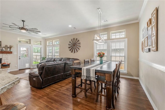 dining space featuring a fireplace, crown molding, dark hardwood / wood-style flooring, and ceiling fan