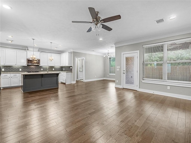 unfurnished living room with crown molding, sink, dark hardwood / wood-style floors, and ceiling fan with notable chandelier