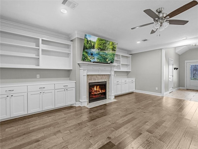 unfurnished living room with ceiling fan, a high end fireplace, and light hardwood / wood-style flooring