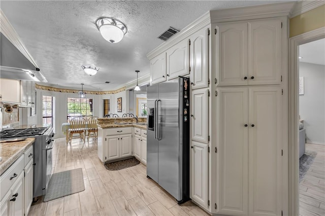 3003 Aztec St, College Station, TX 77845 - kitchen featuring stainless steel appliances, a peninsula, a textured ceiling, pendant lighting, and white cabinetry