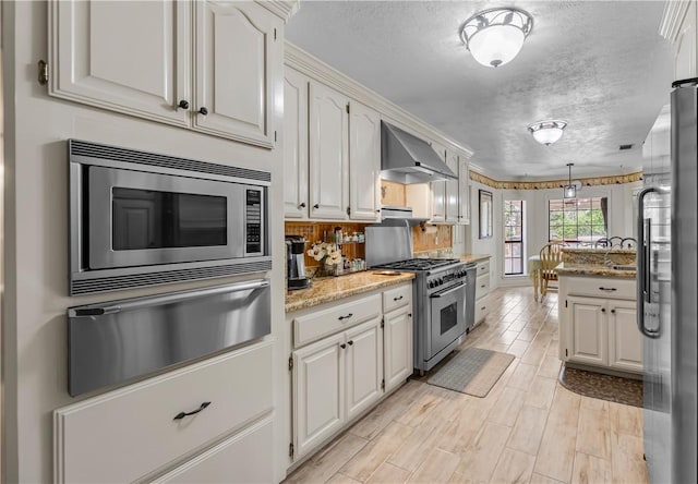3003 Aztec St, College Station, TX 77845 - kitchen with high end appliances, a warming drawer, wall chimney range hood, a textured ceiling, and light stone counters