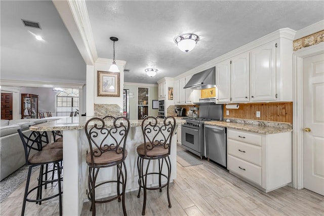 3003 Aztec St, College Station, TX 77845 - kitchen with wall chimney exhaust hood, appliances with stainless steel finishes, a breakfast bar, white cabinets, and open floor plan