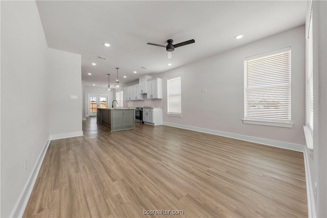 unfurnished living room featuring light wood-type flooring, ceiling fan, and sink