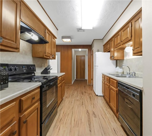 2306 Windsor Dr, Bryan, TX 77802 - kitchen with black appliances, range hood, light wood-style flooring, and light countertops