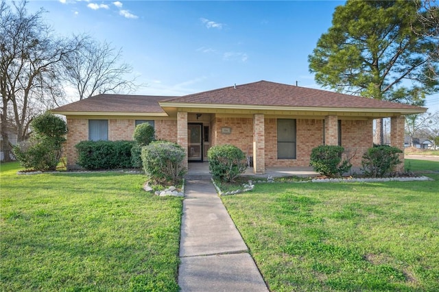 view of front facade featuring a front lawn, a shingled roof, and brick siding