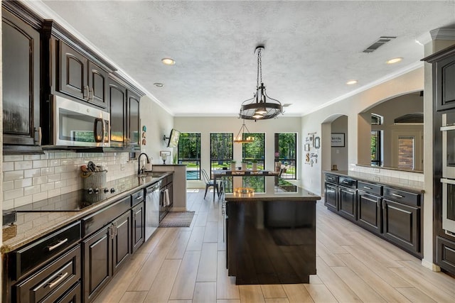 5249 Drake Dr, College Station, TX 77845 - kitchen featuring stainless steel appliances, a sink, a center island, decorative backsplash, and dark brown cabinetry