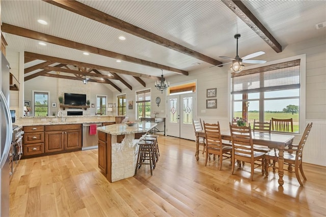 kitchen featuring stainless steel dishwasher, lofted ceiling with beams, a kitchen island, and light wood-type flooring