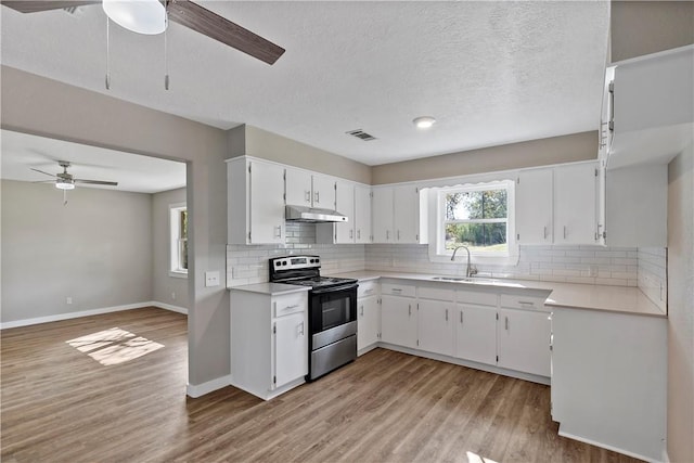 kitchen with decorative backsplash, a textured ceiling, light hardwood / wood-style flooring, white cabinets, and stainless steel range with electric cooktop