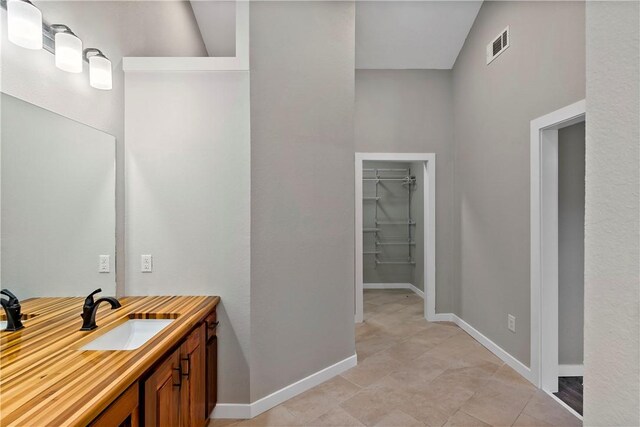 bathroom featuring tile patterned floors, vanity, and lofted ceiling