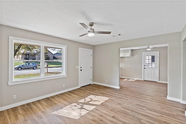 empty room with ceiling fan, a textured ceiling, and light hardwood / wood-style flooring