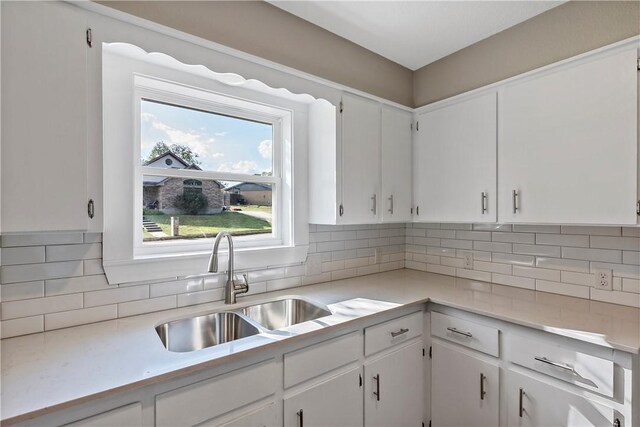 kitchen with white cabinets, backsplash, and sink