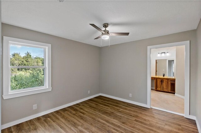 unfurnished bedroom with wood-type flooring, ensuite bath, and ceiling fan