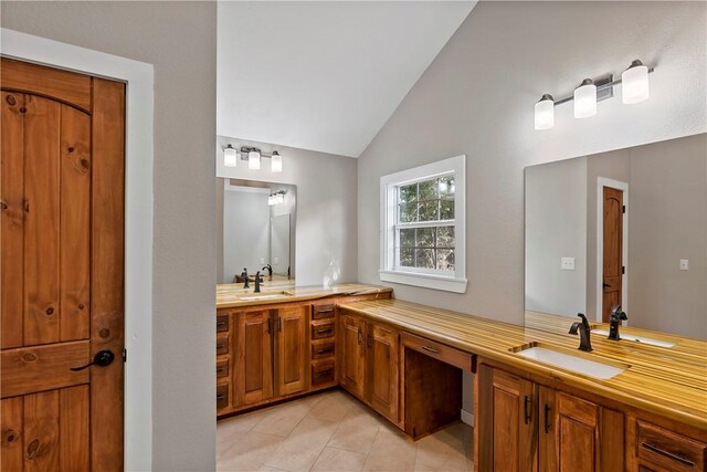 bathroom with tile patterned flooring, vanity, and lofted ceiling