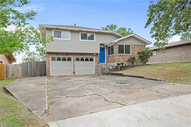 1436 Magnolia Dr, College Station, TX 77840 - tri-level home with a front lawn, brick siding, concrete driveway, an attached garage, and fence