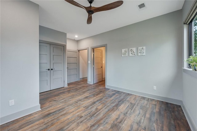 unfurnished bedroom featuring a ceiling fan, visible vents, dark wood finished floors, and baseboards