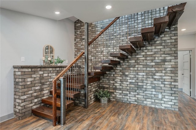 stairway featuring recessed lighting, brick wall, and wood finished floors