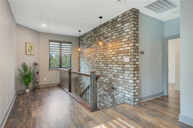 hall featuring dark wood-style flooring, visible vents, attic access, an upstairs landing, and baseboards