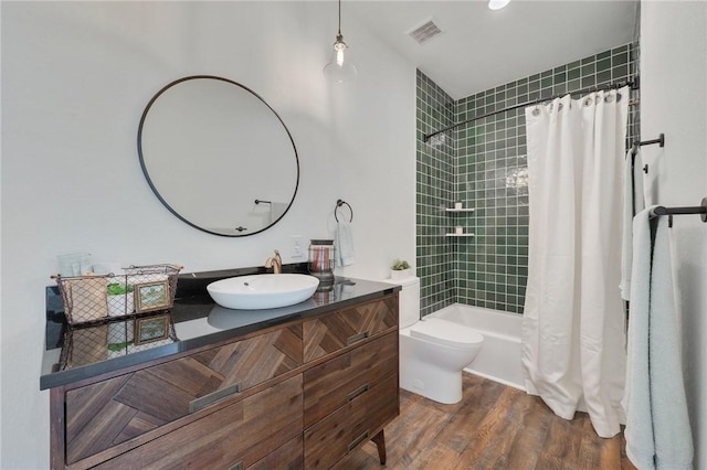 bathroom featuring toilet, wood finished floors, vanity, visible vents, and shower / bath combination with curtain