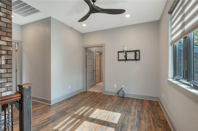 empty room with dark wood-style floors, visible vents, and baseboards