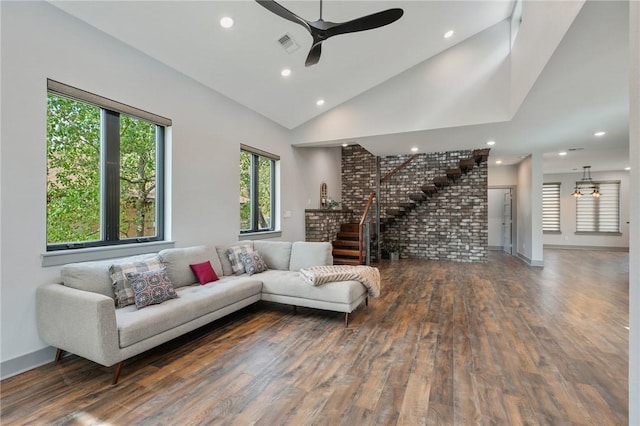 living room featuring ceiling fan, high vaulted ceiling, dark wood-type flooring, and stairway