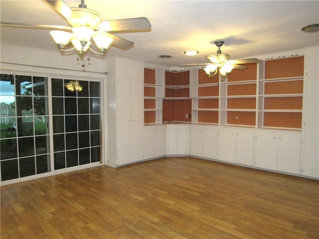 spare room with wood finished floors and ceiling fan with notable chandelier