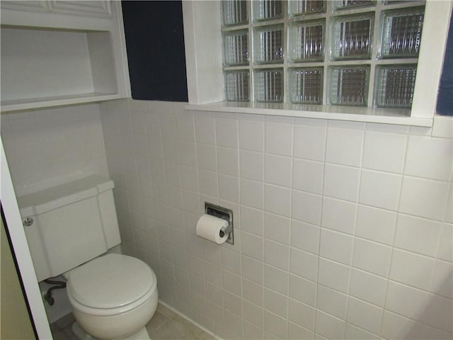 bathroom featuring tile patterned floors, toilet, and tile walls