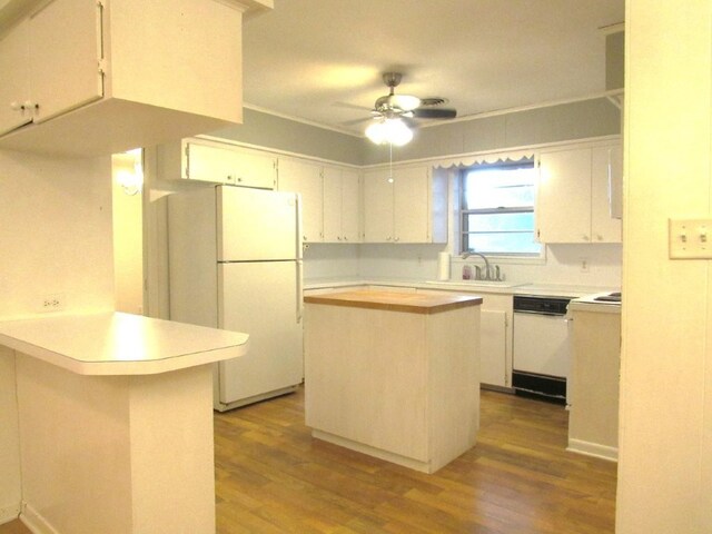 kitchen with a sink, wood finished floors, white appliances, a ceiling fan, and a peninsula