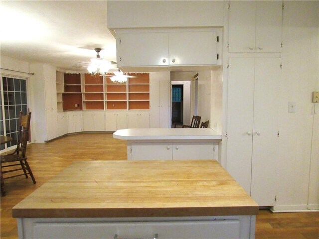 kitchen with wood finished floors, ceiling fan, white cabinets, and built in features