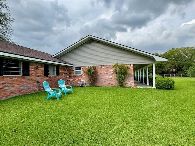 back of property featuring a lawn and brick siding