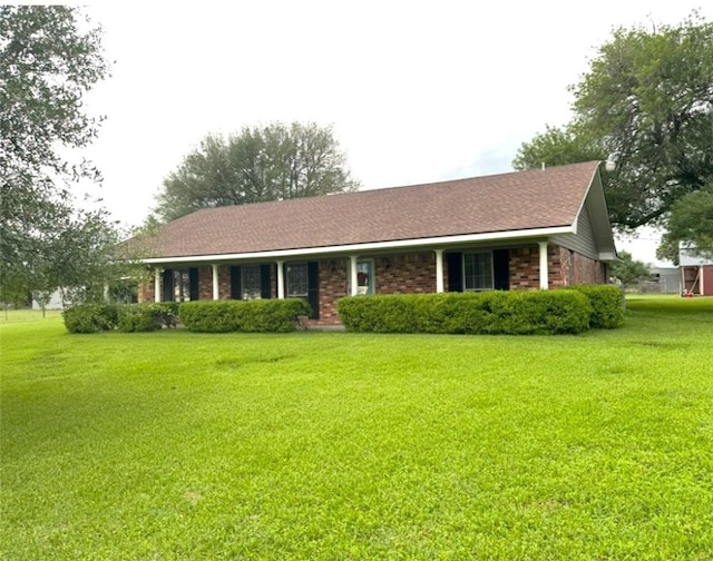 single story home featuring roof with shingles, brick siding, and a front lawn
