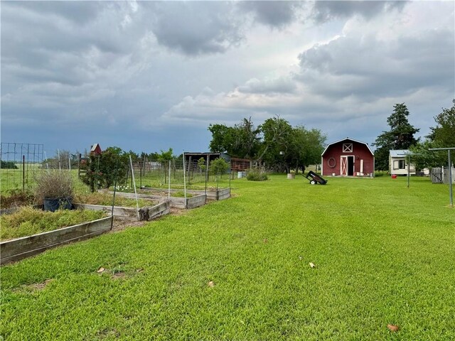 view of yard featuring fence, an outdoor structure, a garden, and a barn