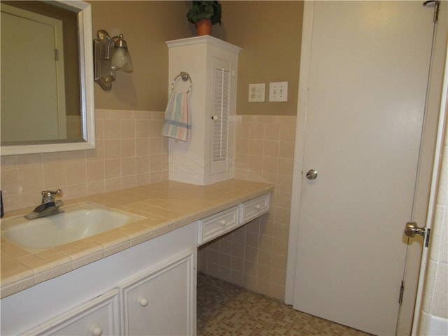 bathroom featuring tile walls, wainscoting, and vanity