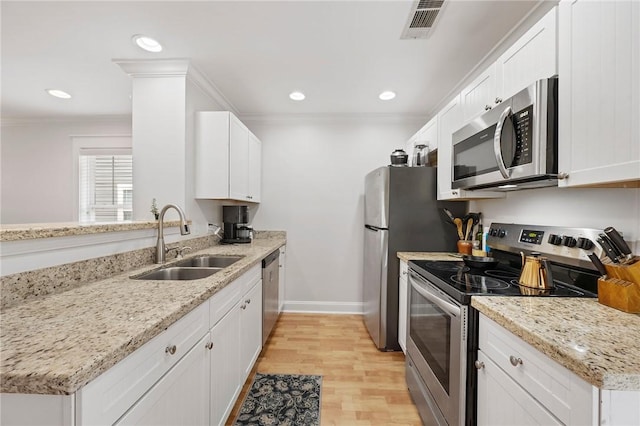 1725 Harvey Mitchell Pkwy, College Station, TX 77840 - kitchen with appliances with stainless steel finishes, a sink, crown molding, light wood finished floors, and white cabinets
